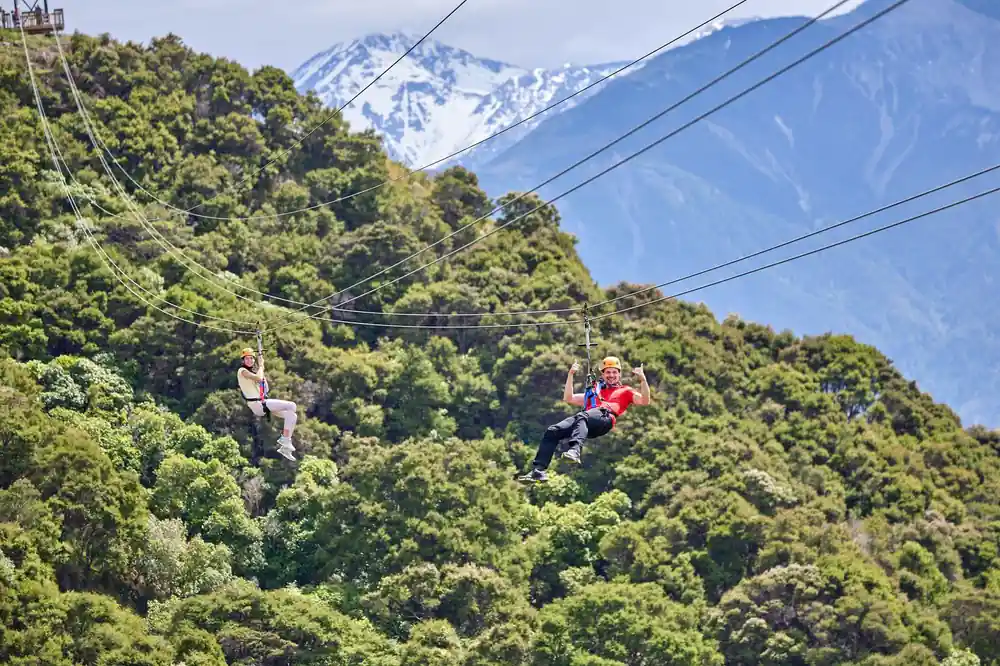 Riders on the wire above the bush with snow peaks beyond